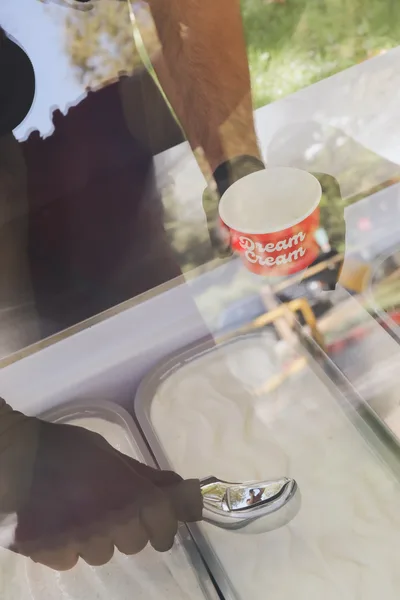 Server scooping fresh gelato into a Dream Cream cup at the cart